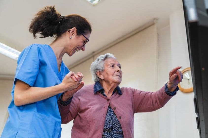 Ältere Frau, die in einem Pflegeheim Hilfe von einer Krankenschwester erhält.