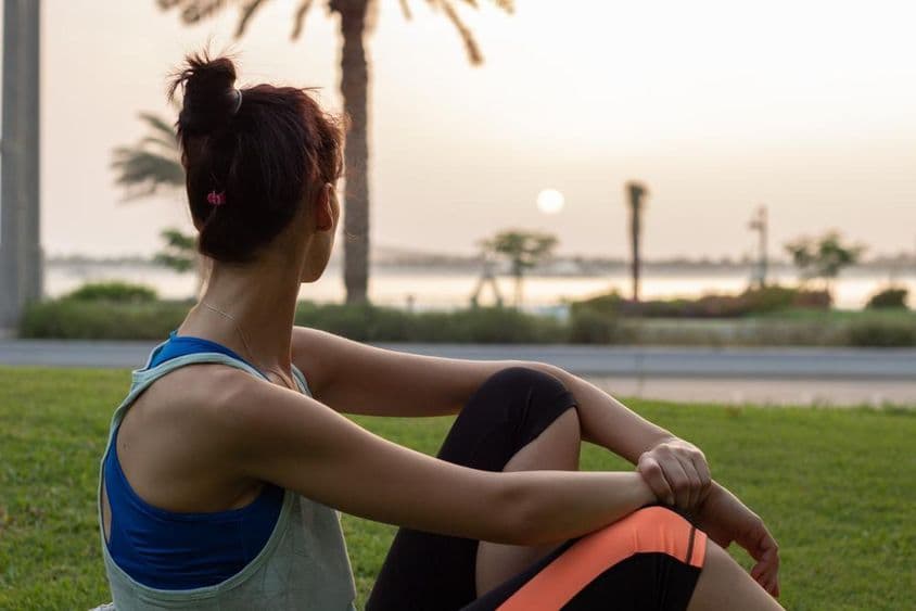 Junges Mädchen ruht sich nach Yoga im Park an der Abu Dhabi Corniche aus.
