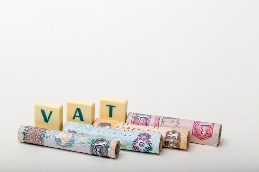 Die Buchstaben VAT über Banknoten des VAE-Dirhams.