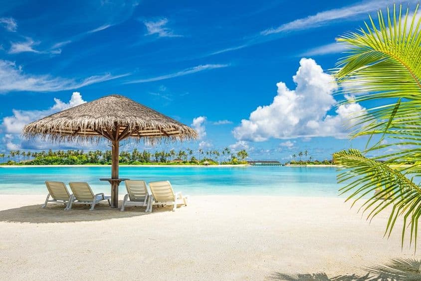 Maledivischer Sandstrand mit Sonnenschirm und Liegestuhl.