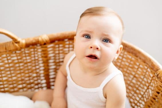 Ein Baby in einer geflochtenen Wiege zu Hause.