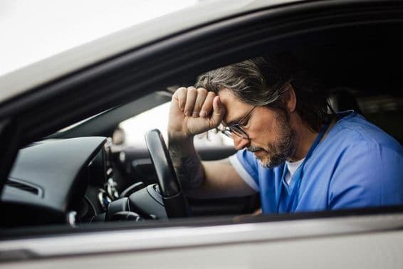 Arzt im Auto, erschöpft.