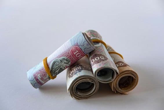 Eine Sammlung von UAE-Dirham-Währung und Münzen, aufgerollt und gestapelt.