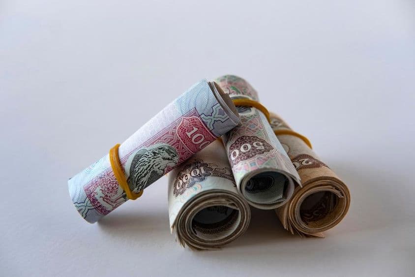 Eine Sammlung von UAE-Dirham-Währung und Münzen, aufgerollt und gestapelt.