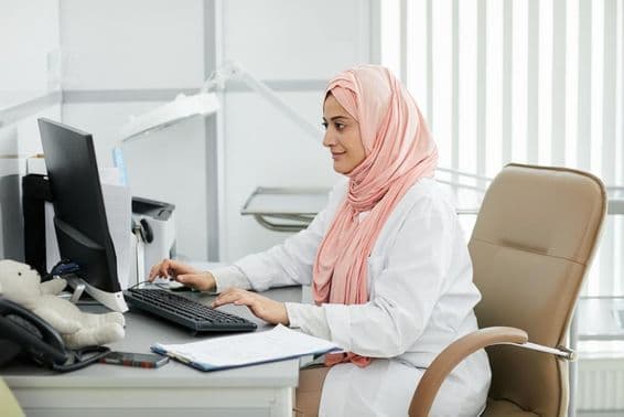 Eine junge Frau aus dem Nahen Osten mit Hijab arbeitet als Krankenschwester in einer medizinischen Klinik.