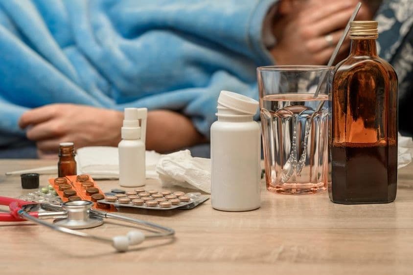 Ein Mann mit Erkältung und Fieber liegt im Bett.