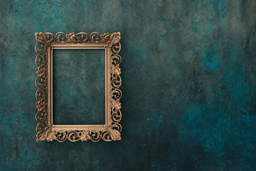 Vintage offenes Bronzerahmen auf blau-grün gealterter Wand.