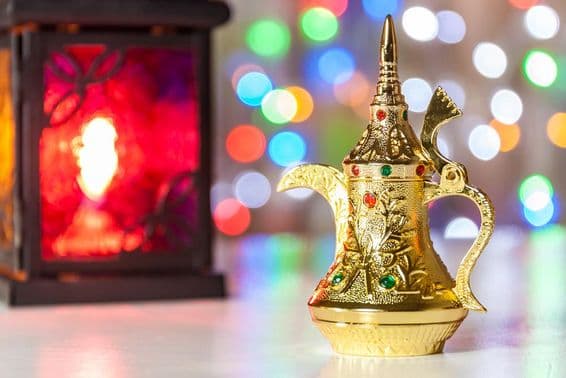 Arabische Kaffeekanne und Lampe mit bunten, verschwommenen Lichtern im Hintergrund.