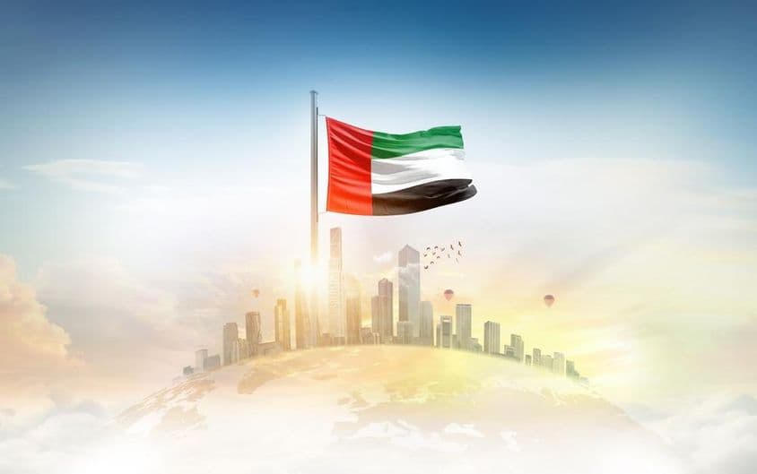Flagge der Vereinigten Arabischen Emirate weht vor Wolkenkratzern.