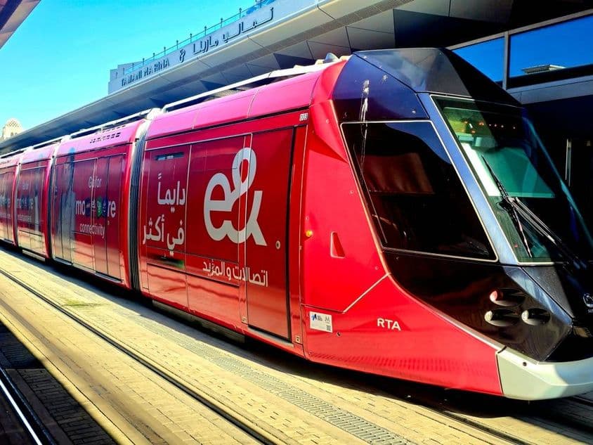 Eine rote Straßenbahn, die auf einem Bahnsteig mit großen Fenstern und elegantem Design geparkt ist.