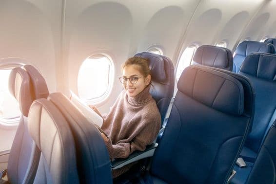 Asiatische Frau liest eine Zeitschrift im Flugzeug.