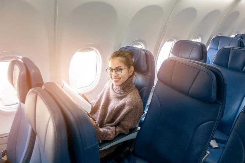 Asiatische Frau liest eine Zeitschrift im Flugzeug.