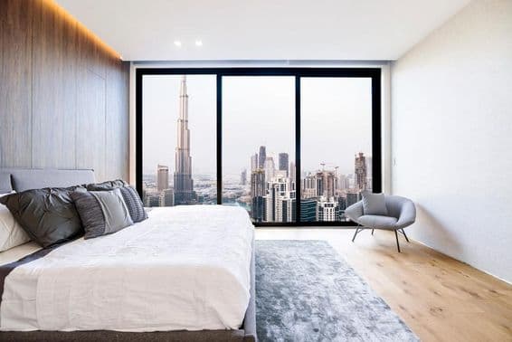 Modernes Schlafzimmer mit weißer Decke und Holzdekoration, Blick auf Hochhaus und Dubai Innenstadt.