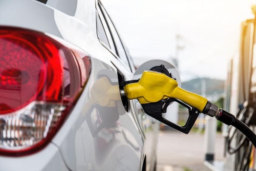 Mann in Dubai, der Benzin an einer Tankstelle in ein Auto pumpt.