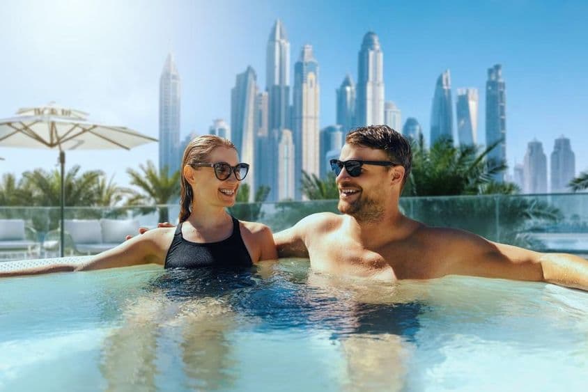 Fröhliches junges Paar entspannt in einem Außenwhirlpool in einem Hotel in Dubai.