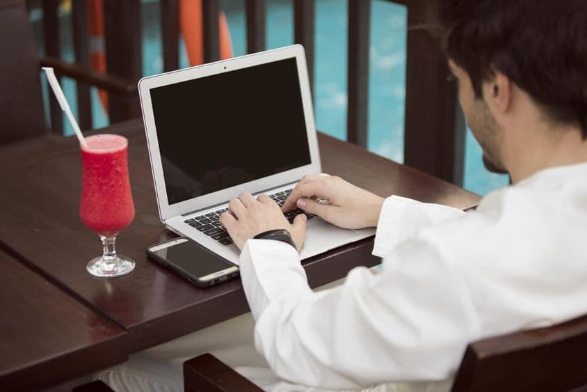 Arabischer junger Geschäftsmann arbeitet mit einem Laptop in einem Café.
