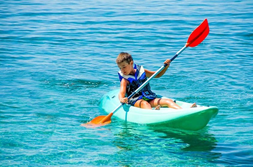Junge mit Rettungsring während der Kajakstunden in den Sommerferien.