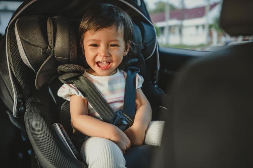 Glückliches Kind sitzt in einem Autokindersitz.