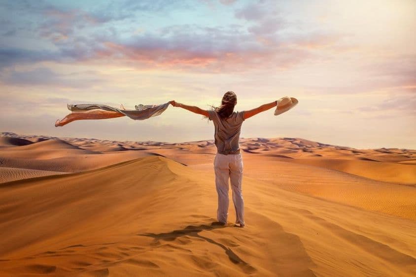 Eine Touristin steht in der Roten Wüste, Dubai, schwenkt ihr Tuch in der heißen Luft.