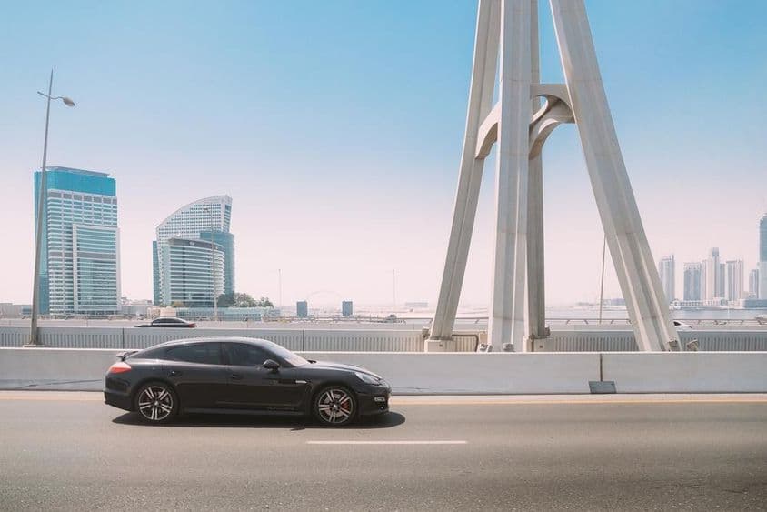 Schwarzer Porsche Panamera fährt auf einer Straße in Dubai.