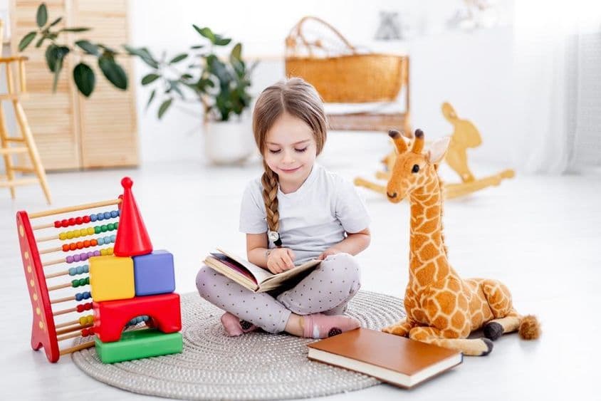 Ein kleines Mädchen zwischen Spielzeugen in einem hellen Kinderzimmer.