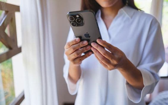 Eine Frau nutzt ein iPhone 15 Pro Max zu Hause.