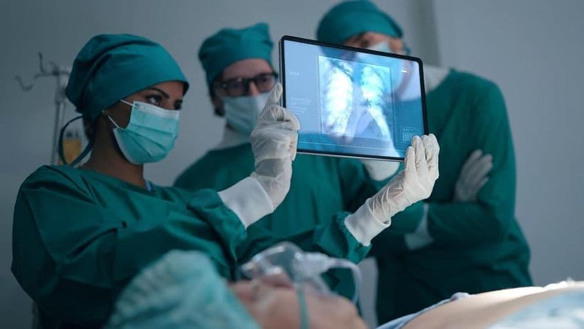 Professionelles medizinisches Team bespricht und überprüft ein Röntgenbild eines Patienten mit Lungenentzündung.