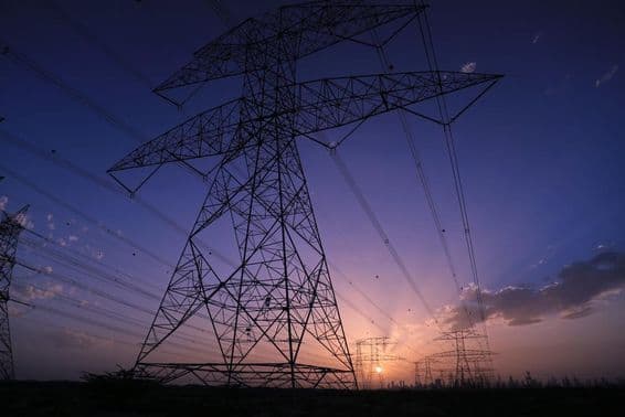 Hochspannungstürme bei Sonnenuntergang mit Blick auf die Dubai-Skyline.