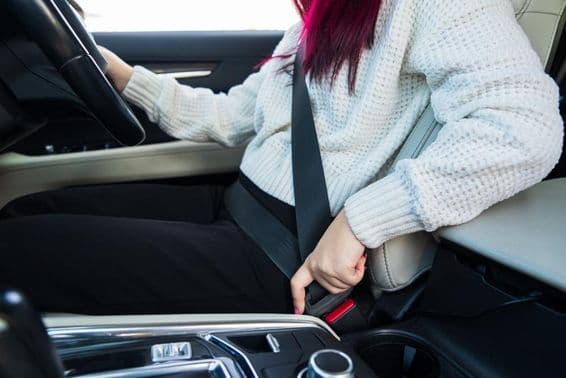 Weibliche Fahrerin schnallt ihren Sicherheitsgurt an.