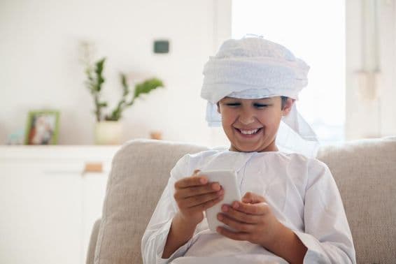 Arabischer Junge benutzt ein Smartphone zu Hause.