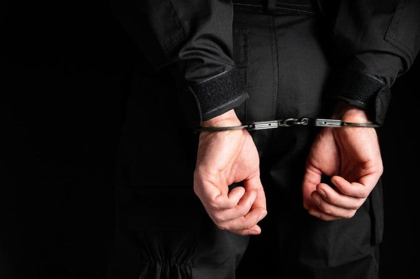 Hände eines Verbrechers in Handschellen.