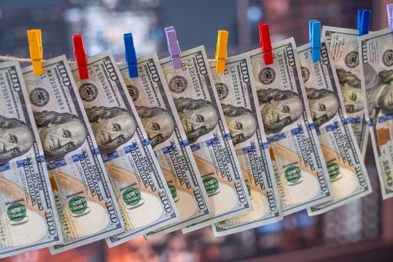 Ein 100 US-Dollar-Schein, der mit Holzklammern an einer Wäscheleine hängt.