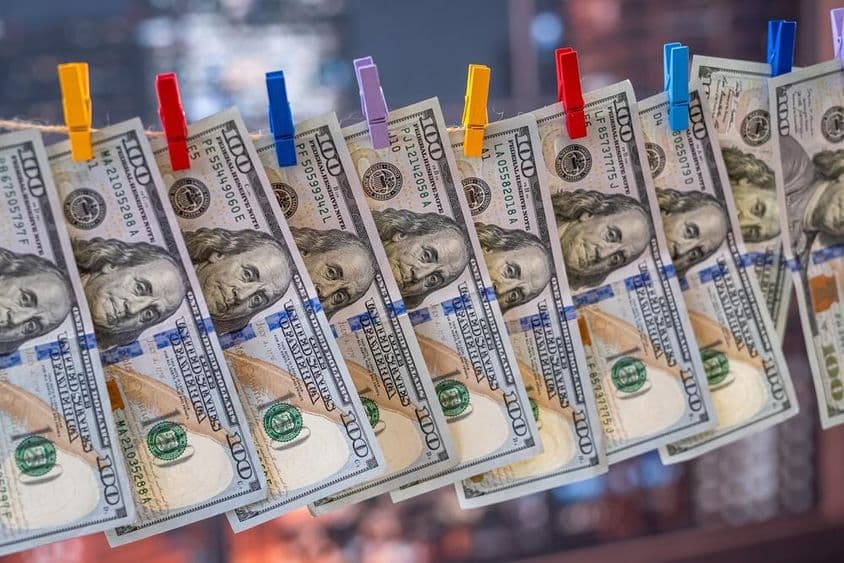 Ein 100 US-Dollar-Schein, der mit Holzklammern an einer Wäscheleine hängt.