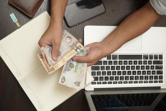 Ein Mann zählt einen Stapel Dirham-Banknoten der Vereinigten Arabischen Emirate.