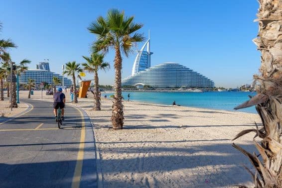 Ansicht des Burj Al Arab entlang eines palmenbeschatteten Radweges am Kite Beach Dubai.