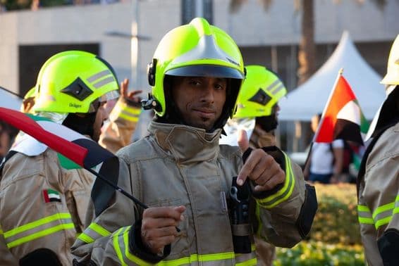 UAE-Feuerwehrleute gehen mit der Flagge der Emirate anlässlich des Nationalfeiertags.