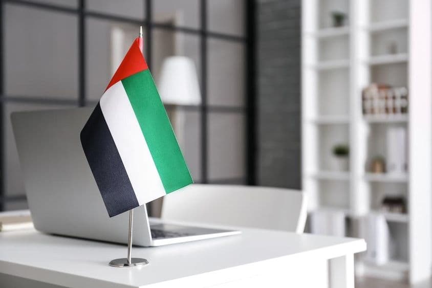 Flagge der Vereinigten Arabischen Emirate auf einem Tisch in einem modernen Büro.