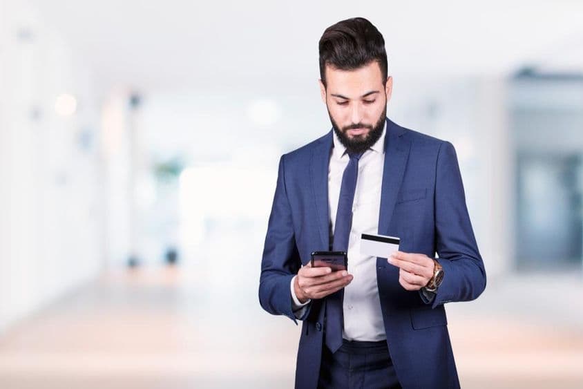 Arabischer Geschäftsmann mit Smartphone und Kreditkarte.