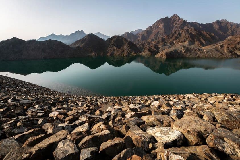 Hatta-Staudamm und Berge, atemberaubender Blick auf reflektierende Felsen und Berge bei Sonnenaufgang.