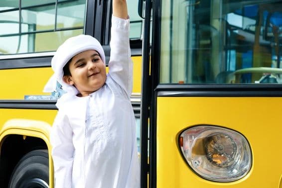 Arabisches Grundschulkind in der Nähe eines gelben Schulbusses.