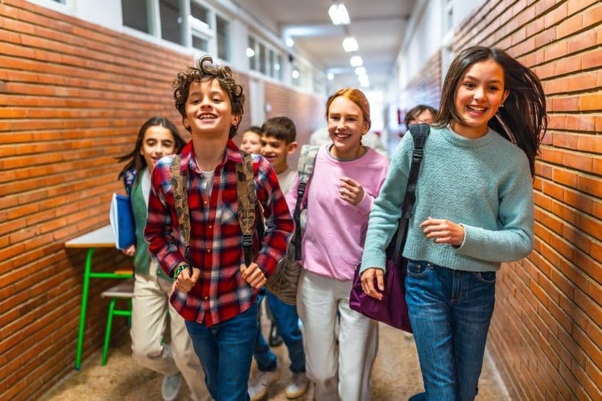 Fröhliche Schüler rennen durch den Schulflur.