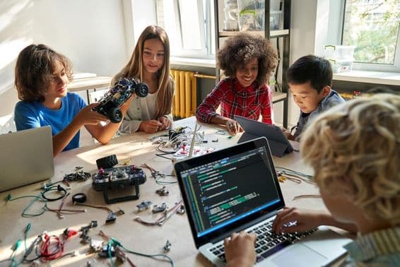 Schulkinder bauen mit Computern und Programmierung Roboterautos.