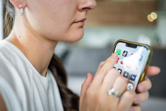 Frau hält ein iPhone mit WhatsApp-Chat-Anwendung auf dem Bildschirm.