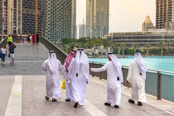 Arabische Männer in traditioneller weißer Kleidung, die in Dubais Innenstadt spazieren.