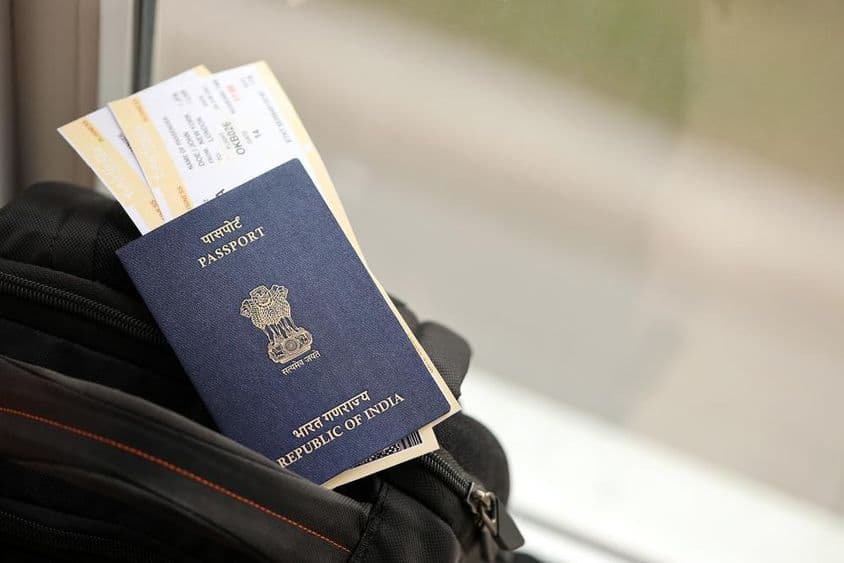 Blauer indischer Reisepass mit Flugtickets auf einem Reise-Rucksack.