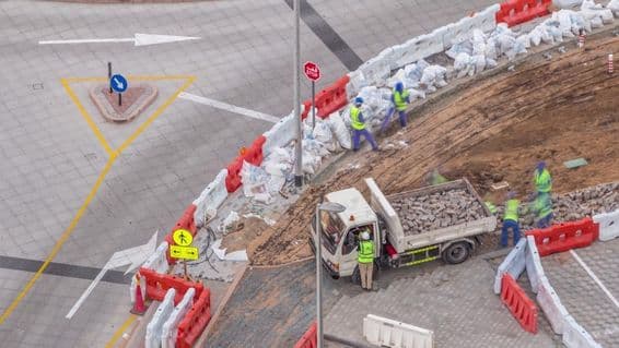 Fußwegreparaturprozess mit vielen Bauarbeitern und Geräten, die den Gehweg und Beton aufbrechen.