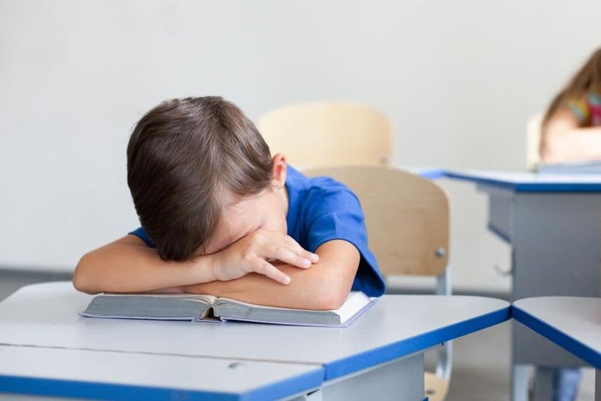 Schulkind schläft während eines langweiligen Unterrichts.