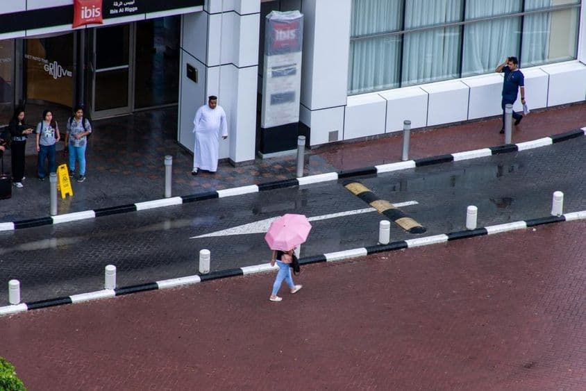 Ein Mädchen mit einem Regenschirm geht im Regen in der Stadt Dubai.