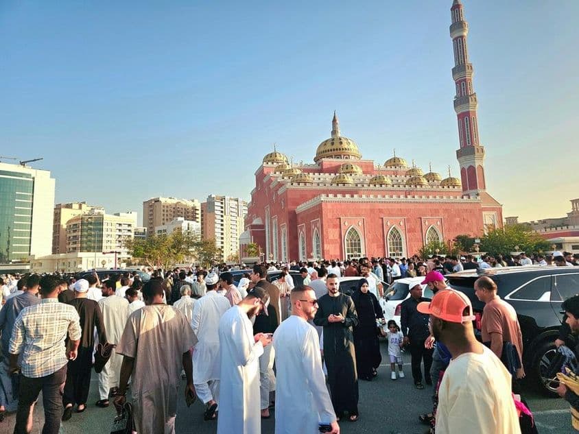 Eine große Menschenansammlung vor einer großen Moschee mit Kuppeln und hohen Minaretten.