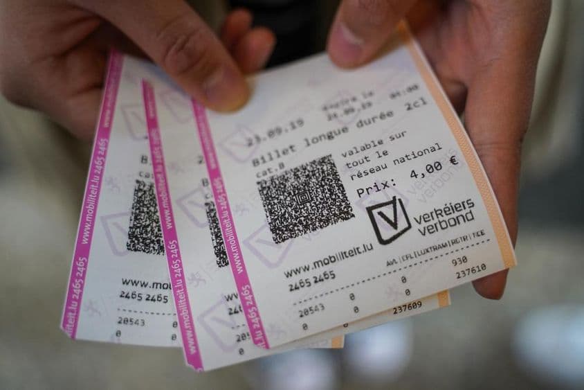 Ein junger Mann hält Tickets in der Hand.